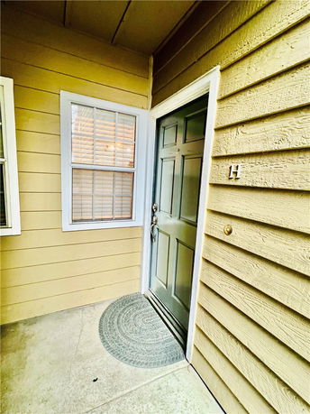 Close-up view of the entrance to a residential building with a green door and yellow siding.