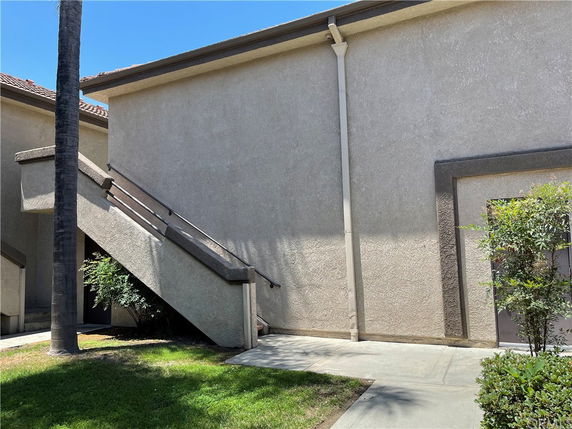 Side view of a two-story building with stairs and beige walls.