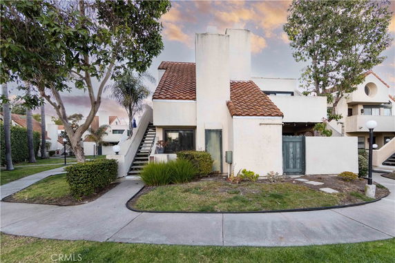 Front view of a two-story house with a staircase and tiled roof.