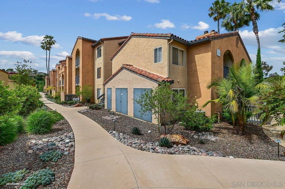 Front view of a multi-story residential building with a walkway and landscaped area.
