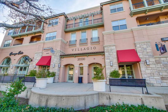 Front view of a multi-story building with red awnings and stone accents.