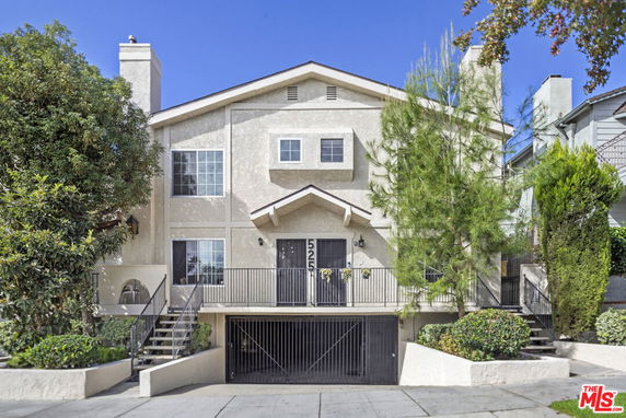 Front view of a multi-story house with gated entry and front steps.