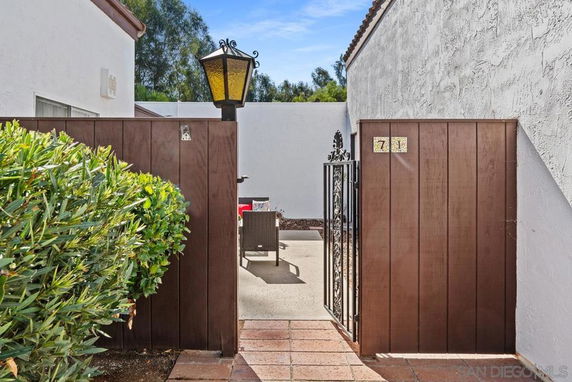 Entrance view of a house with a wooden gate and outdoor seating area.