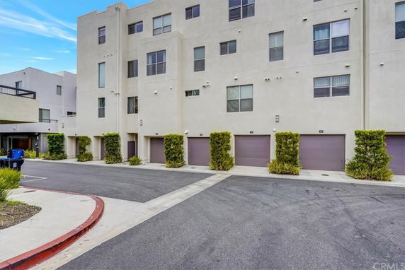 Front view of a multi-story apartment building with multiple garage doors at the ground level.