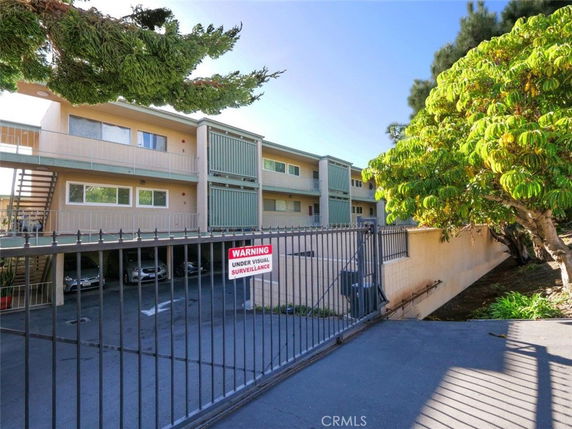 Front view of a multi-story apartment building with balconies and gated parking.