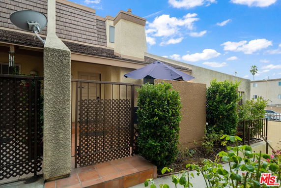 Front view of a house with a fenced patio and satellite dish.