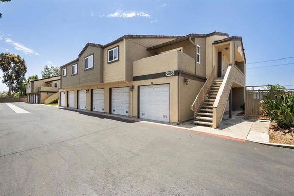 Front view of a multi-story building with garages on the ground level and stair access to upper floors.