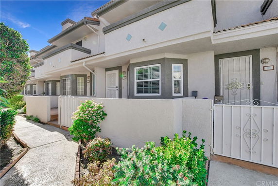 Front view of a multi-story townhouse with white and gray exterior and small gated entrance.