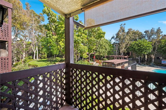 View from a balcony overlooking a swimming pool and garden area.
