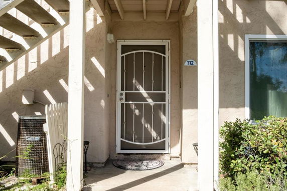 Front view of a house entrance with a security door and house number 112.