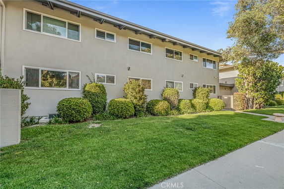 Front view of a two-story residential building with a well-maintained lawn and shrubs.