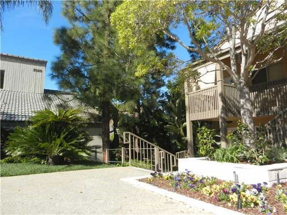 View of a building with a staircase and landscaped area with trees and shrubs.