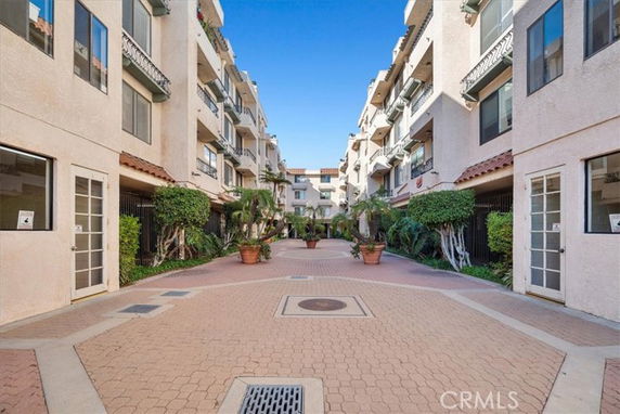 Open courtyard area between multi-story apartment buildings with potted plants.