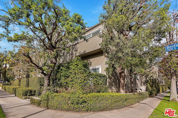 Front view of a multi-story building with trees and hedges.