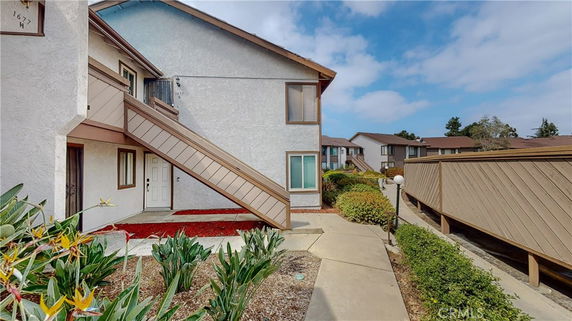 Front view of a two-story residential building with outdoor stairs leading to the upper floor.