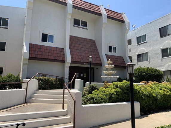 Front view of a multi-story building with a tiled roof and staircase leading to the entrance.