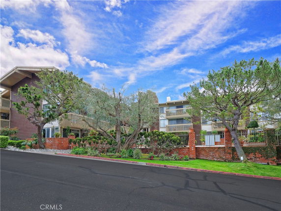 Front view of a multi-story residential building with balconies and landscaped gardens.
