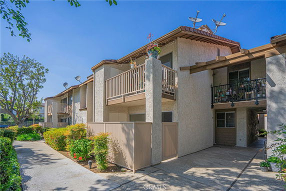 Front view of a two-story apartment building with balconies and satellite dishes.