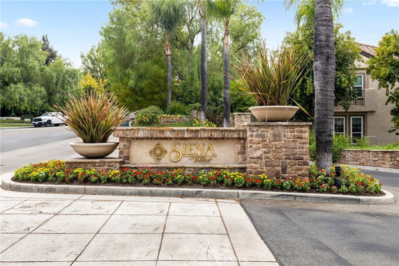 Entrance sign of a residential area with landscaping and stone wall.
