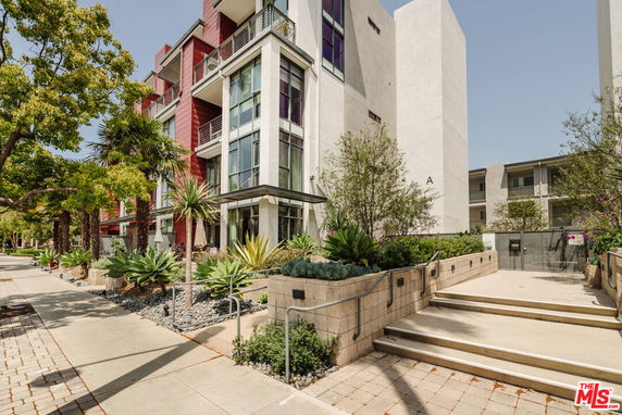 Front view of a modern multi-story building with large windows and a landscaped entrance.