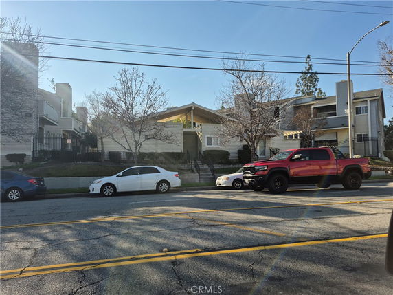 Front view of a multi-story residential building with cars parked in front.