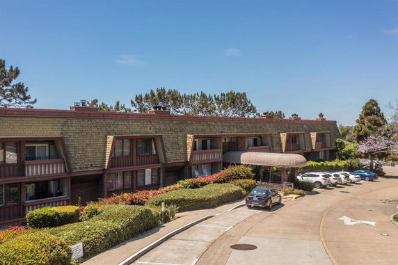 Front view of a multi-story building with a parking area in front.