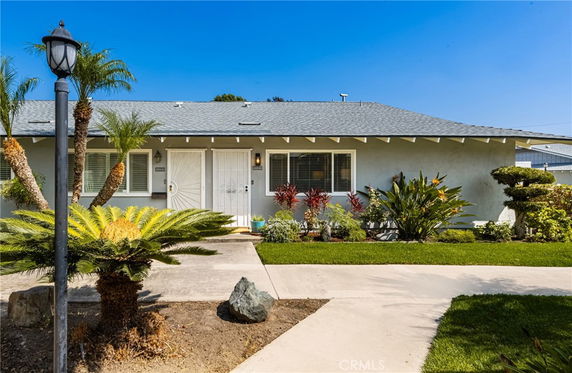 Front view of a single-story house with a gray exterior and a landscaped front yard.