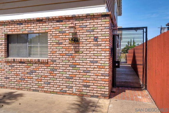 Front view of a brick exterior with a window and gated entry.