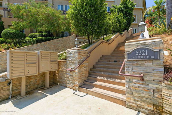 Front view of a building with stone steps leading up from the street and multiple mailboxes.