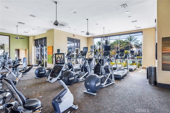 Interior view of a gym with various exercise equipment and large windows.