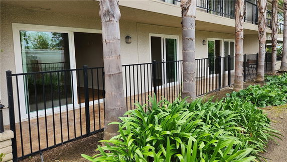 Front view of a building with a ground floor patio and glass sliding doors.