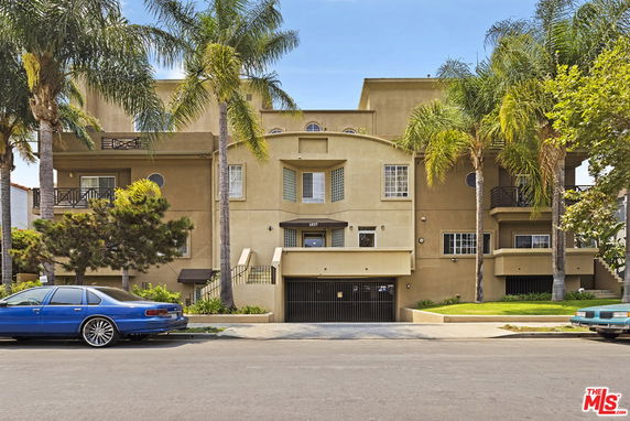 Front view of a multi-story building with balconies and a gated entrance.