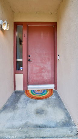 Front view of a house entrance with a red door and a colorful mat.