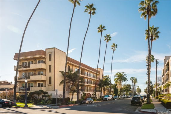 Front view of a multi-story building with balconies and palm trees.