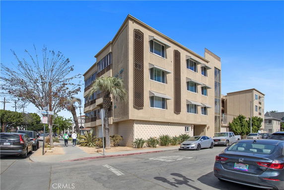 Front view of a four-story apartment building on a street corner.