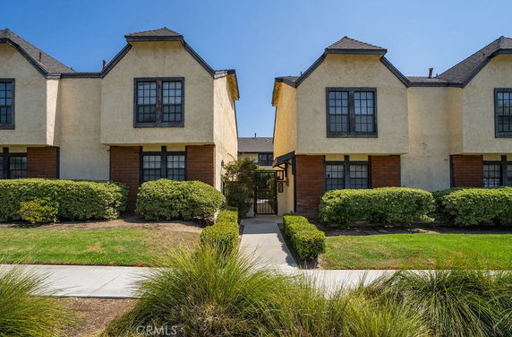 Front view of a two-story residential building with peaked roofs and large windows.