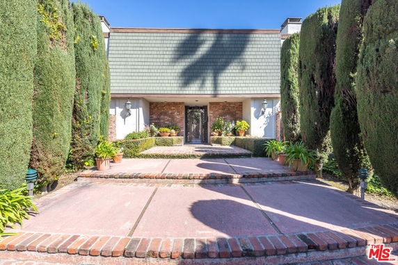Front view of a house with a brick exterior and green roofing.