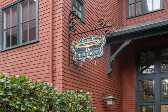 Front view of a multi-story brick house with decorative signage.
