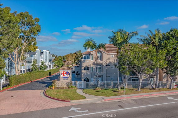Front view of a multi-story residential building with a paved driveway and surrounding greenery.