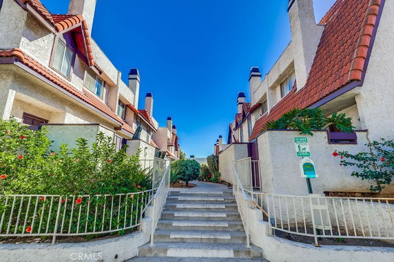 Front view of a multi-story residential building with red roofs and chimneys.
