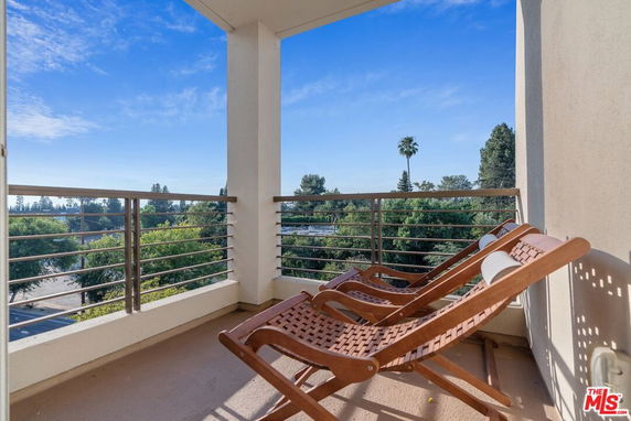 Outdoor balcony view with trees and sky in the background.