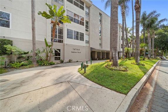 Front view of a multi-story building with large windows and landscaped entrance.