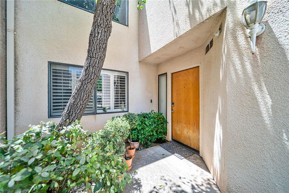 Front view of a house entrance with a wooden door and a window with shutters.