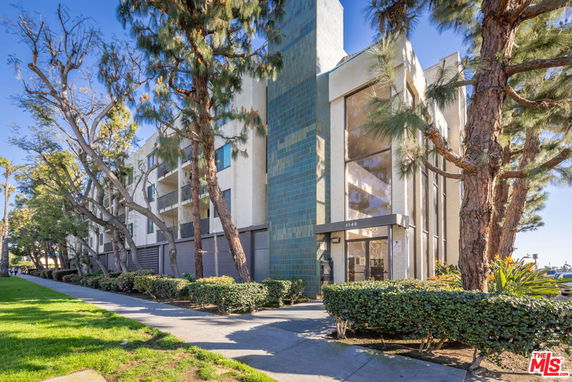 Front view of a multi-story building with a glass entrance and balconies.
