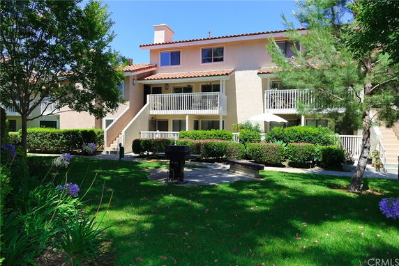 Front view of a multi-story building with balconies and a red tile roof.