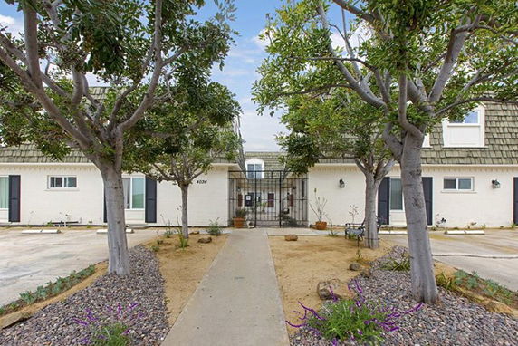 Front view of a two-story residential building with a walkway and trees.