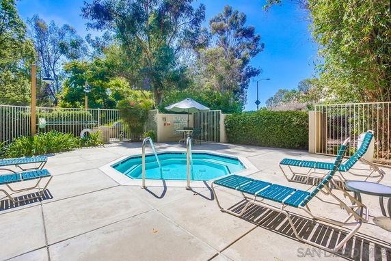 Outdoor swimming pool area with lounge chairs and surrounding fence.