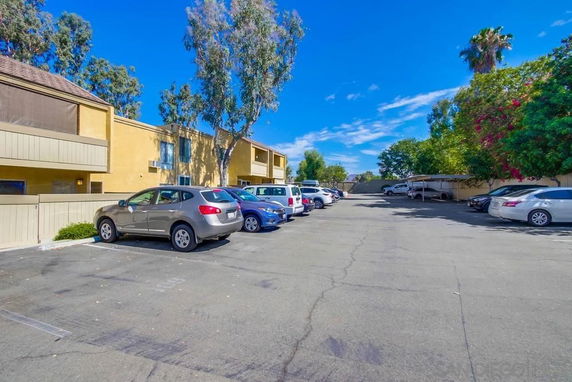 Outdoor parking area with multiple parked cars in front of a residential building.