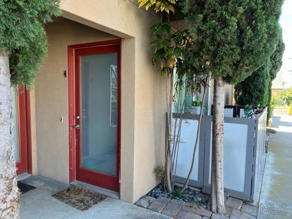 Entrance of a building with a red door and surrounding greenery.