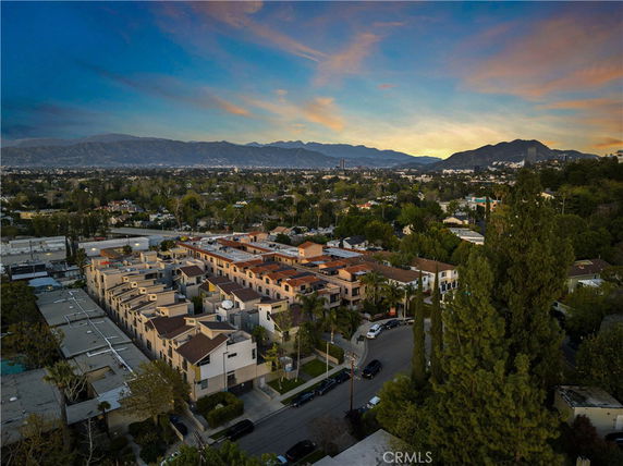 Panoramic view of a residential area with rows of houses and mountains in the background.